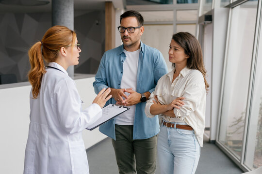 Doctor consulting couple at clinic discussing medical care