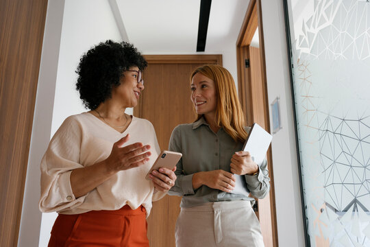 Colleagues walking and talking in a modern office hallway