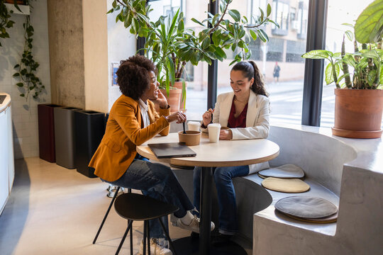 Coworkers having coffee break and discussion at workplace cafe