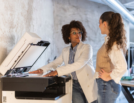 Professional colleagues discussing ideas at the office printer
