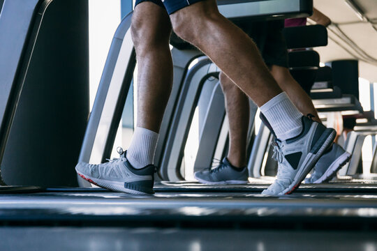 Legs of athletes running on treadmills in health club