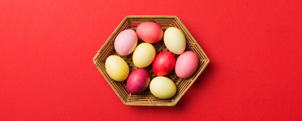 Multi colors Easter eggs in the woven basket on colored background . Pastel color Easter eggs. holiday concept with copy space