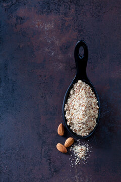Spoon of almond flour and almonds on rusty ground