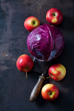 Red cabbage, apples and cleaver on rusty ground