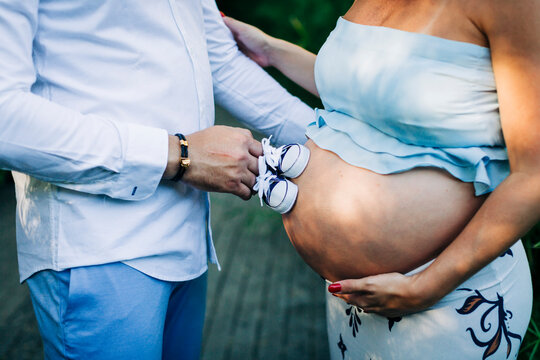Man touching belly of pregnant woman with baby booties