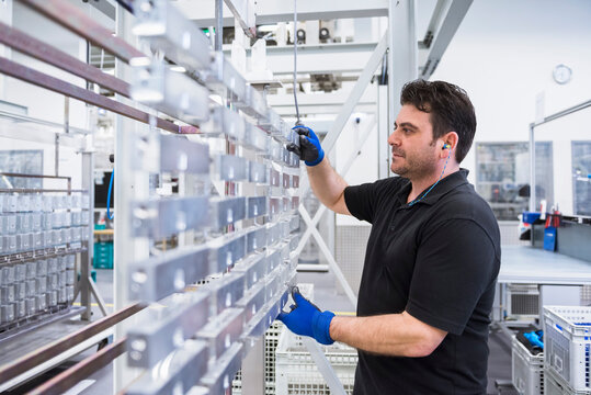 Man working in factory shop floor hanging products on rack