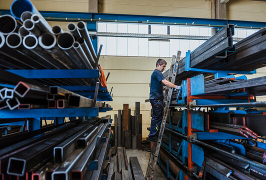 Man working with metal bars on a shelf in a factory