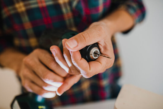 Close-up of woman holding chuck of electric drill while standing at home