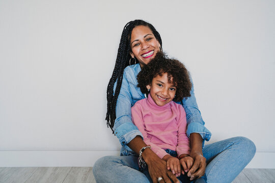 Portrait of happy mother and her little daughter sitting together on the floor