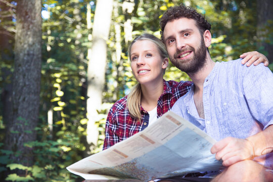 Smiling young couple with map in a forest