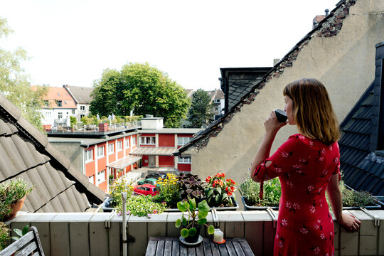Young woman relaxing with cup of coffee on balcony looking at distance