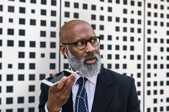 Mature businessman talking on the phone, wearing earphones