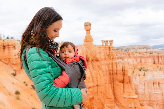 Woman carrying her daughter in a baby carrier at hoodoos in Bryce Canyon, Utah, USA