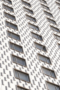Geometric white facade detail where modern architecture design uses repeating windows pattern and textured surface for abstract building background