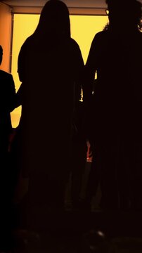 A group of people silhouetted against a bright yellow background, possibly at sunset.