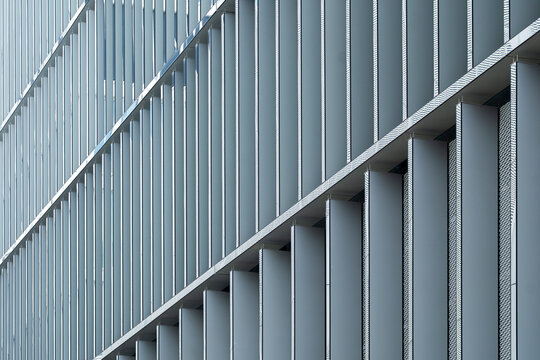 Modern exterior facade with curved gray louvers and repeating lines forms an abstract architecture pattern for clean contemporary background
