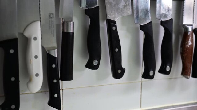 Professional kitchen knives hanging on magnetic wall rack