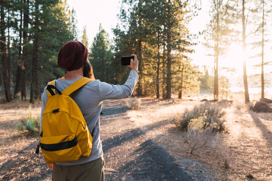 USA, North California, young man taking a selfie in a forest near Lassen Volcanic National Park
