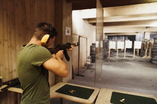 Man aiming with a rifle in an indoor shooting range