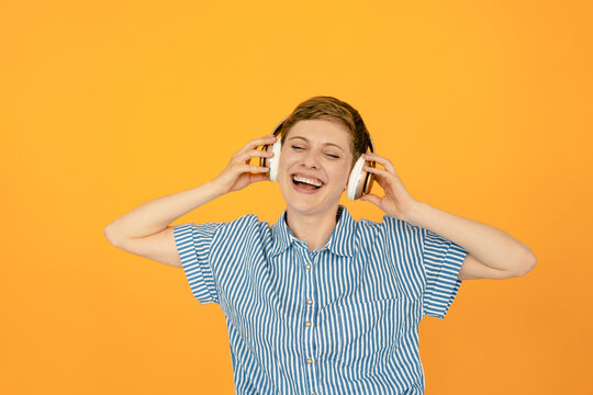 Portrait of happy woman listening to music with orange background