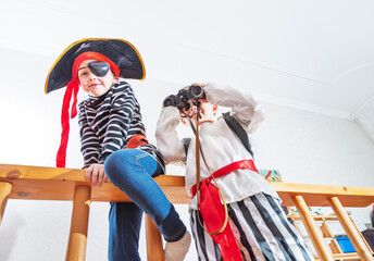 Children playing pirates in costume at home interior