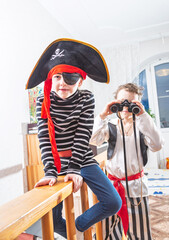 Children playing pirates in costume at home interior
