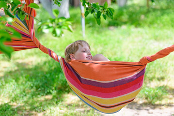Child relaxing in colorful hammock outdoors in nature