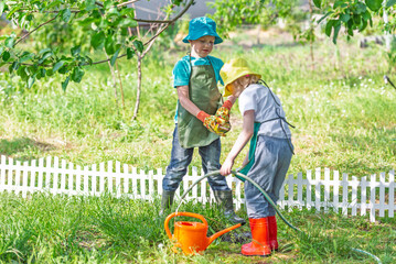 Children gardening outdoors with vegetables and watering plants