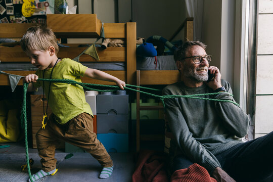 Little boy pulling his father speaking on phone