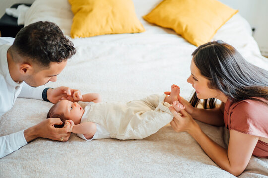 Happy parents holding baby boy on bed at home