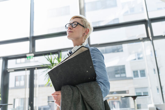 Smiling woman in office building carrying file folder