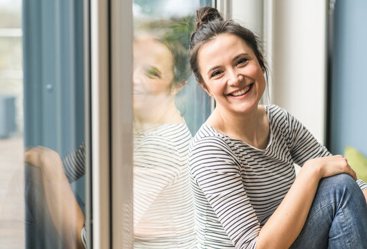 Portrait of happy woman sitting at the window at home