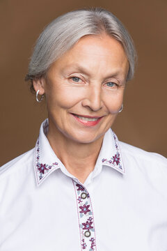 Portrait of smiling senior woman with grey hair wearing embroidered blouse