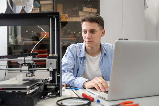 Student setting up 3D printer, using laptop
