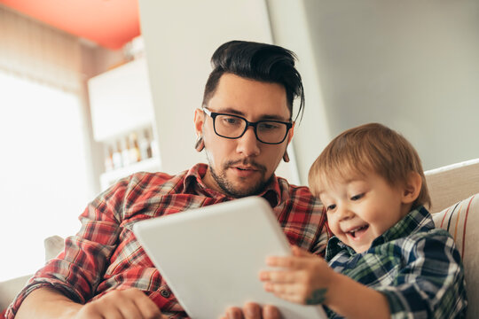 Father and son on couch using tablet