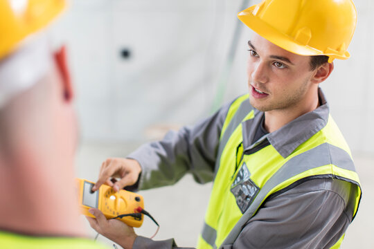 Electricians working with voltmeter on construction site