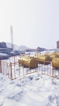 In a cold, snowy setting, golden storage tanks are neatly arranged within a protective barrier. The distant mountains and additional structures hint at remote work in harsh conditions.