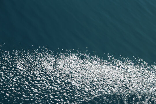 Sunlight sparkling on blue ocean water surface texture
