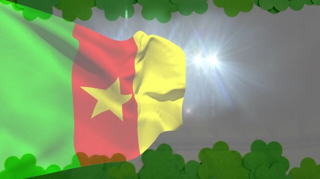Wind gusts moving Cameroon flag, rippling star and folding while lights flaring, clovers rising