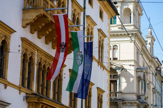 Flags of Austria, Styria region and the European Union hanging on historic architecture. European city center, government building and travel concept