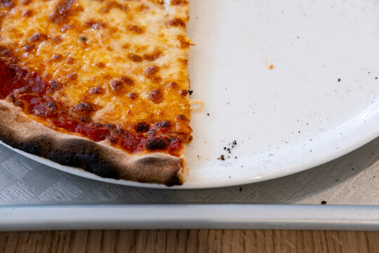 Documentary closeup of baked pizza slice on a plate showing melted cheese and crisp crust as a simple food meal idea for lunch time