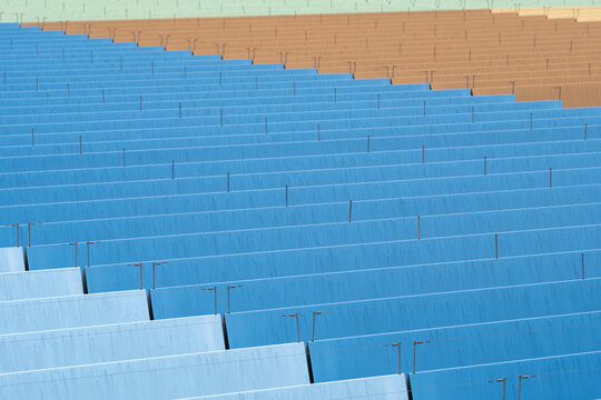 Empty sports venue stadium bleachers with blue seats in long rows creating a bold pattern and texture for a clean documentary view