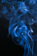 Obraz premium Elegant wisps of blue smoke on a dark background. The smoke creates an abstract and ethereal display of colors and patterns