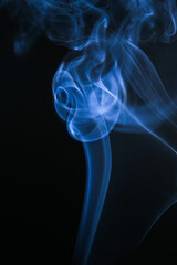 Abstract image of blue smoke gracefully rising with a dark background. The smoke creates an elegant, artistic display