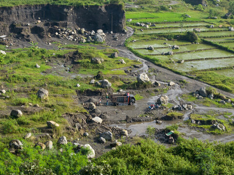 Aerial view of a muddy landscape with patches of vibrant green vegetation and agricultural fields, Klaten Regency, Jawa Tengah, Indonesia.