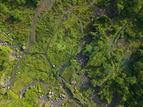 Aerial view of lush green vegetation interspersed with rocky pathways and small dwellings, Kali woro, Klaten Regency, Jawa Tengah, Indonesia.
