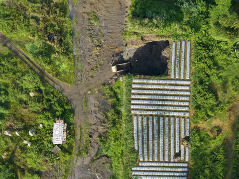 Aerial view of a truck parked next to a field with rows of crops, surrounded by vibrant green vegetation, Kali woro, Klaten Regency, Indonesia.