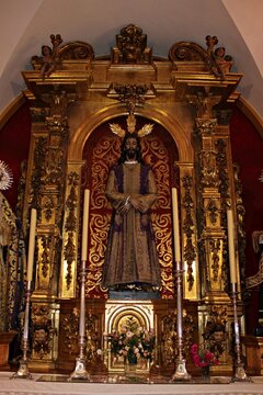 Golden church altarpiece with statue of Jesus Christ inside historic Catholic church, ornate baroque retable with sacred Christian sculpture and candles