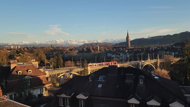 View of Bern, capital city of Switzerland, on a sunny golden light winter sunset with the Alps covered in snow in the background.