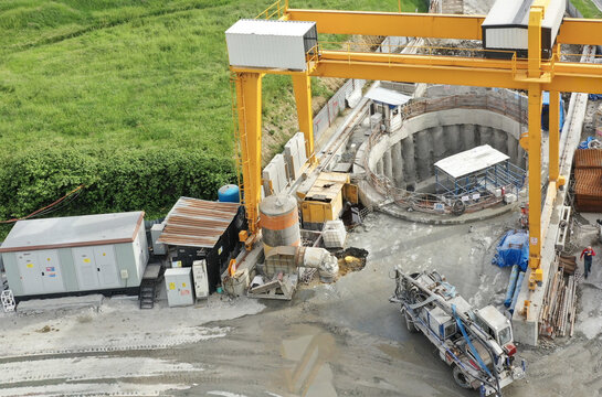 Aerial view of construction site with heavy machinery and tunnel entrance, the yellow metal frame contrasting with the green fields, Avcilar, Istanbul, Turkey.